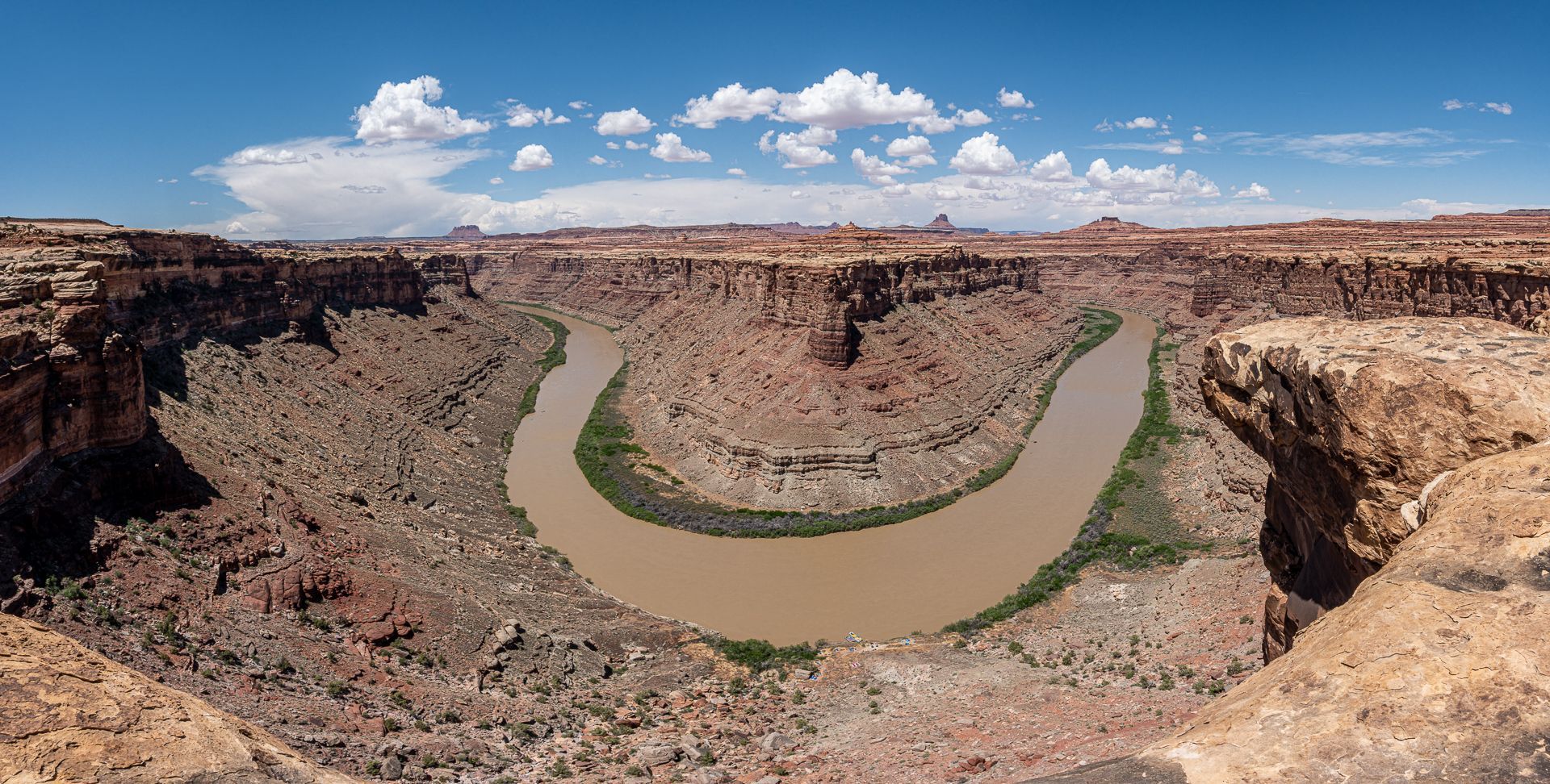 Canyon landscape with a winding river under a blue sky with clouds.