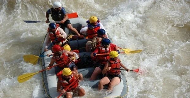 White water rafting: Group of people in a raft navigating through rushing, white water.