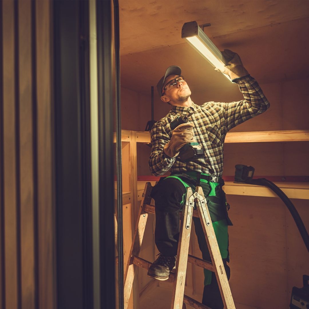 A man is sitting on a ladder holding a light