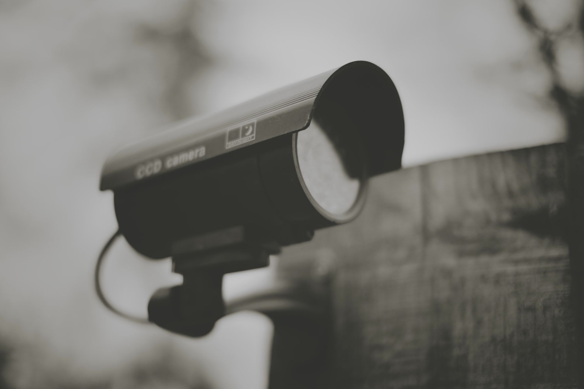 A black and white photo of a security camera mounted on a wall.
