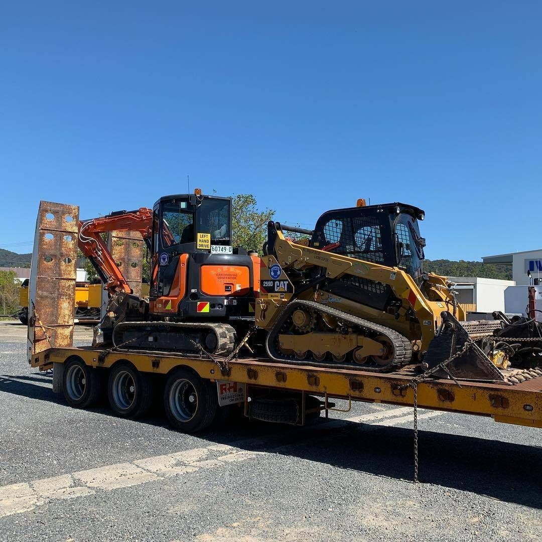 A Orange Excavator and Yellow Skid Steer on a Flatbed Trailer — B & D Bunt Earthmoving Contractors in Coffs Harbour, NSW