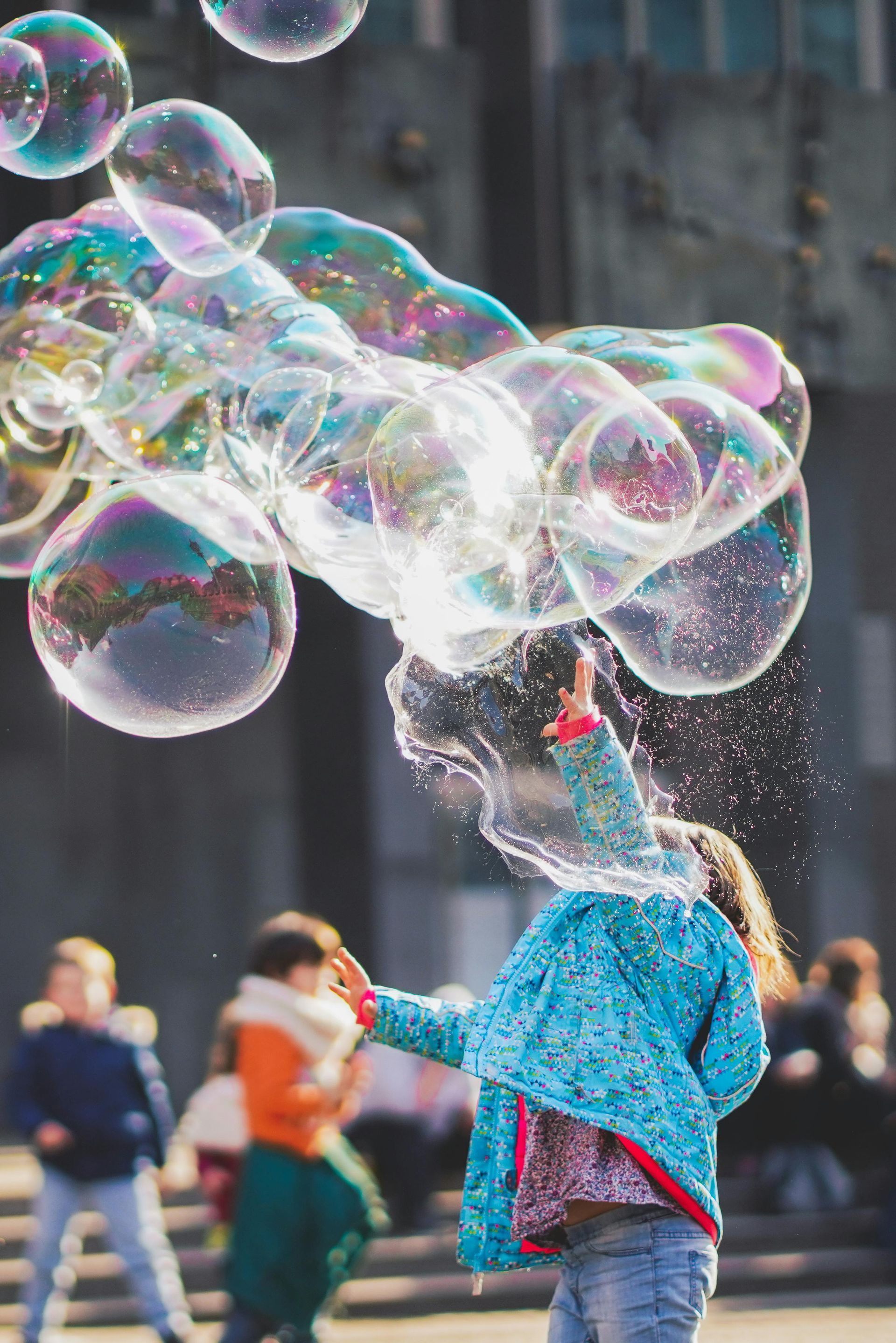 A little girl is blowing soap bubbles in the air.