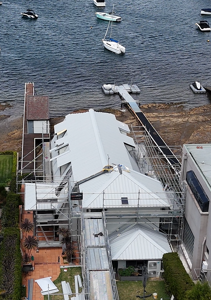 An aerial view of a house under construction next to a body of water.