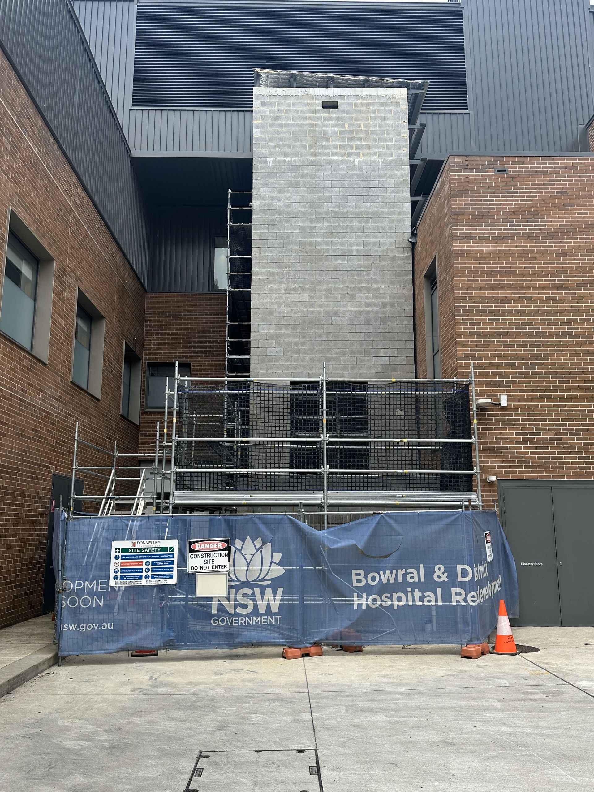 A large brick building with a blue caution sign in front of it.