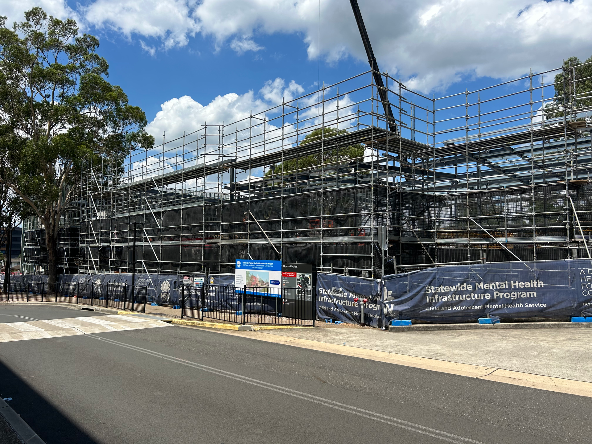 A large building is being built with scaffolding and a crane.