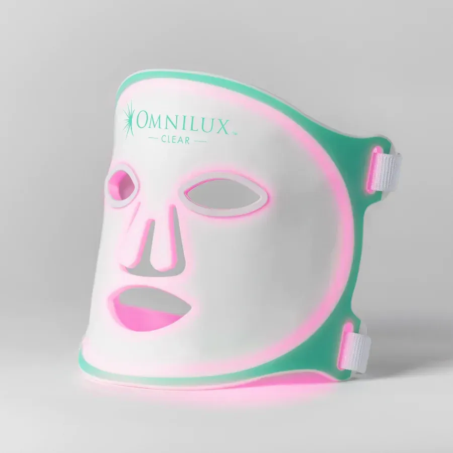 A green and pink led mask is sitting on a white surface.