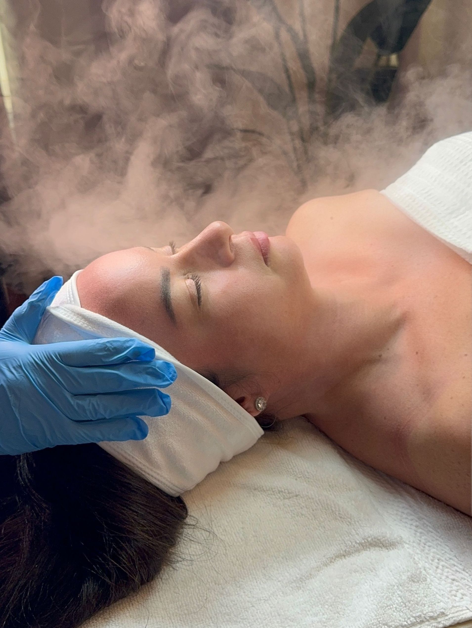 A woman is getting a steam treatment on her face.