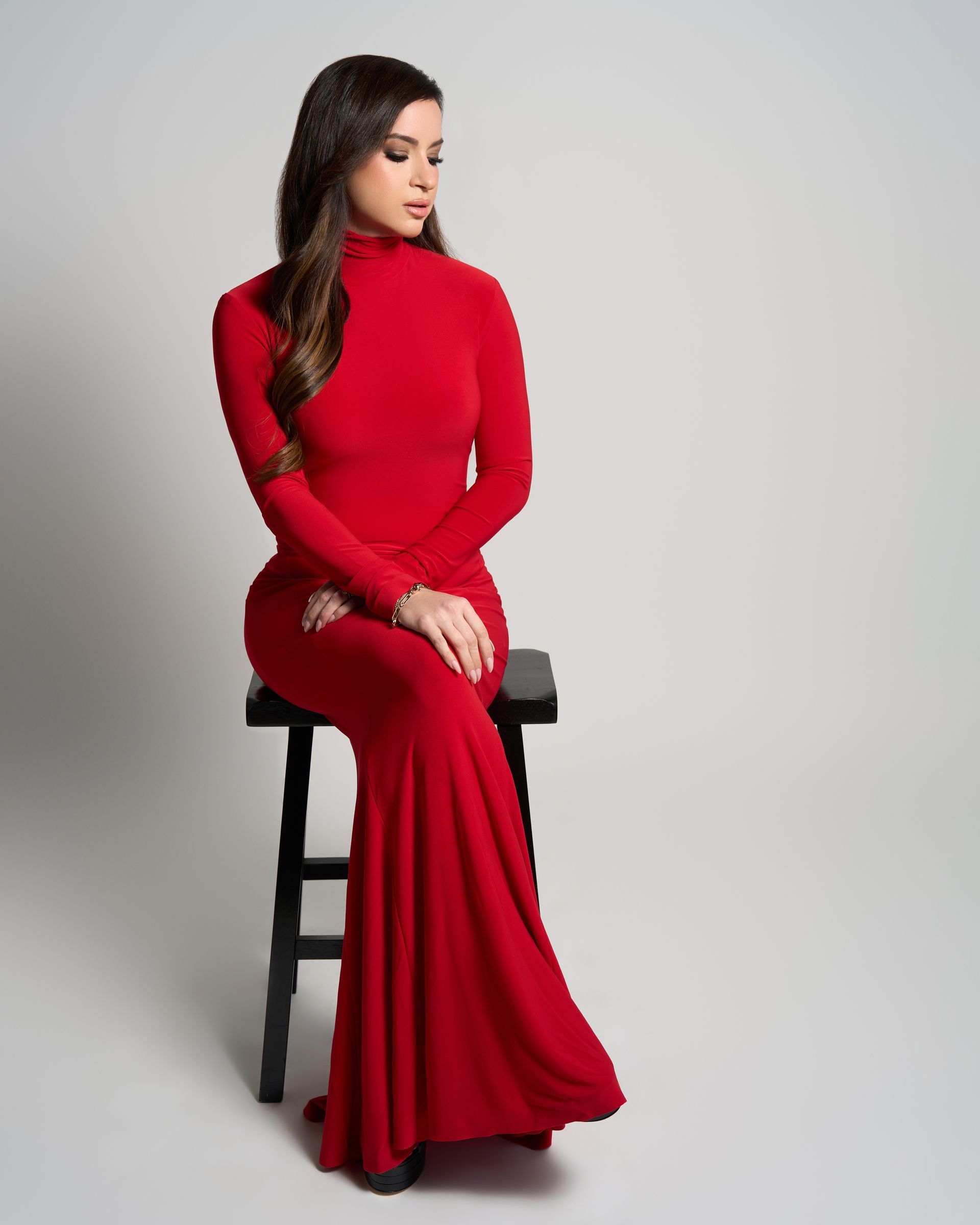 A woman in a red dress is sitting on a stool