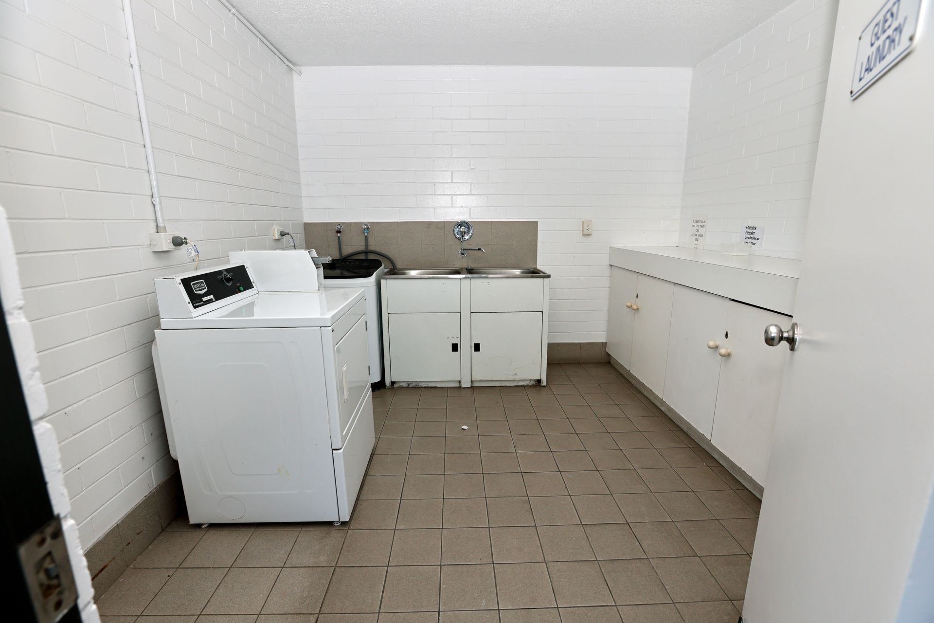 Laundry room with white washer, cabinets, and folding counter on tiled floor