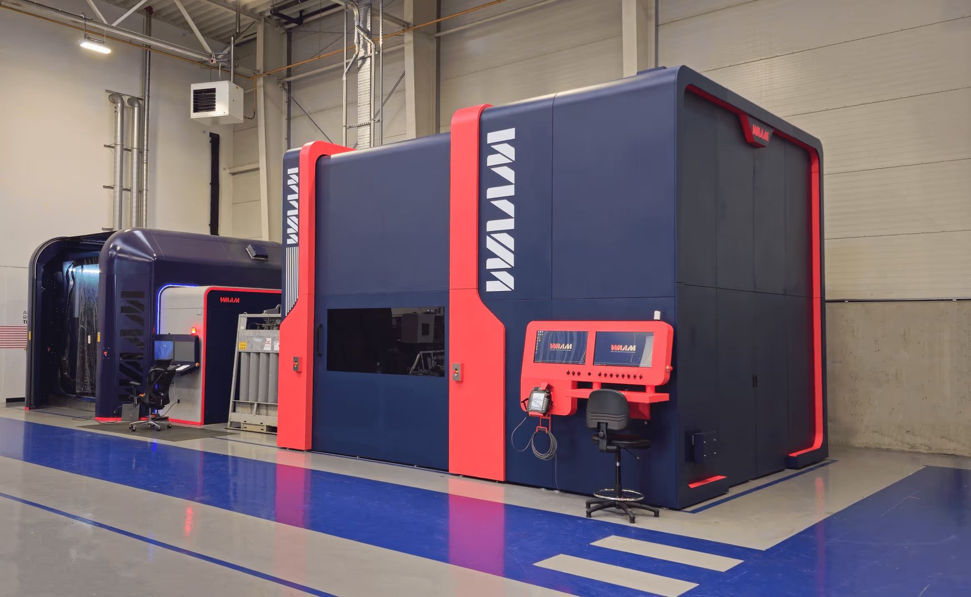 Large industrial machine in a warehouse setting, with red and blue casing, and control panel.