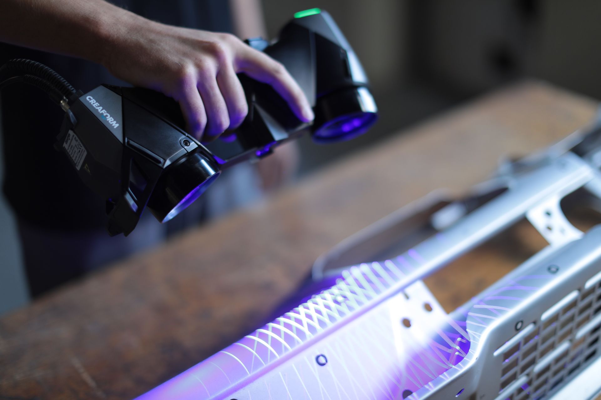 A person is using a 3d scanner to scan a piece of metal.