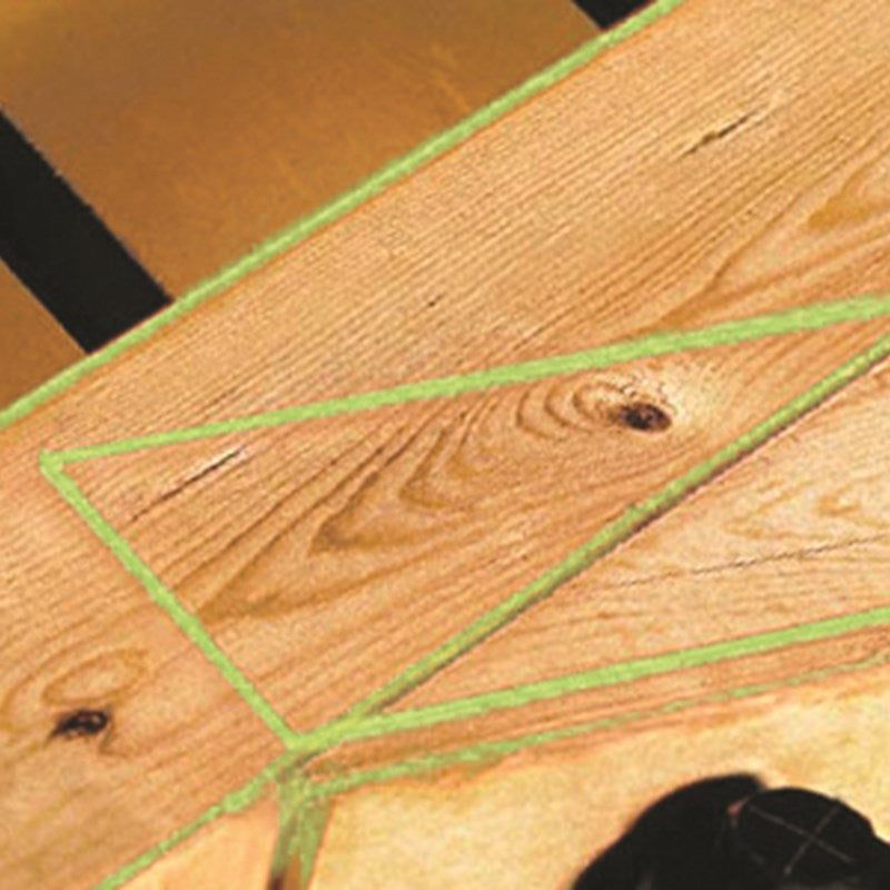Close-up of wooden boards, with green tape outlining a section.