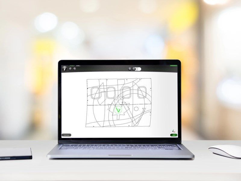 Laptop displaying a black and white diagram of an airplane interior on a white desk with a blurry background.
