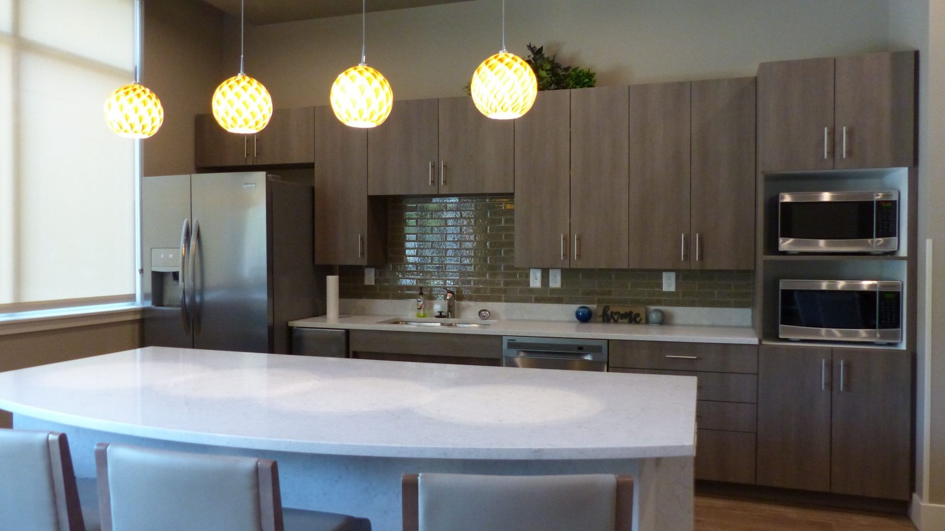 Modern kitchen with white island, pendant lights, wood cabinets, and stainless steel appliances
