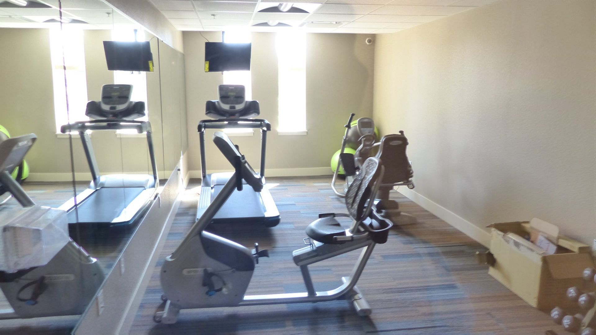 Gym with treadmills, weight benches, mirrors, and boxes along the wall