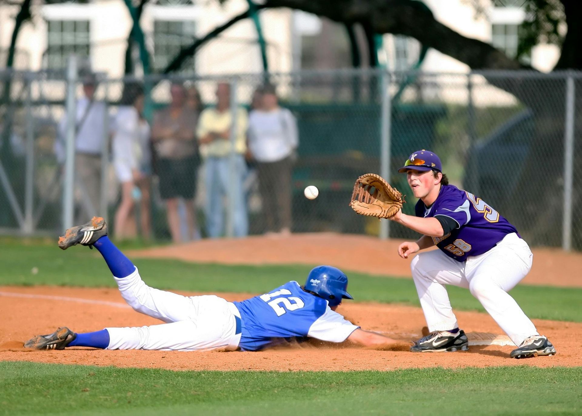 Baseball player sliding into base as another player attempts to catch the ball.