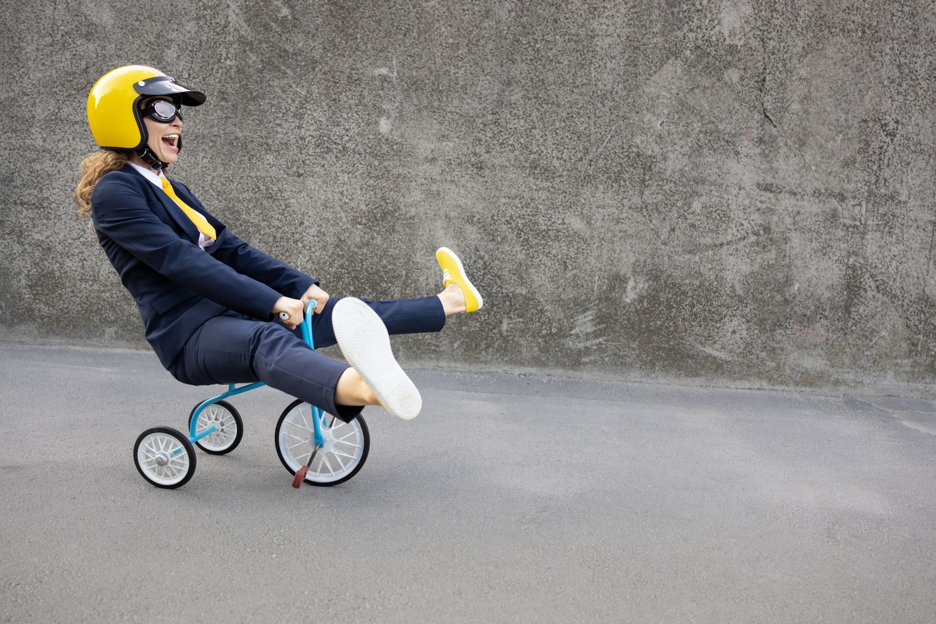 A woman in a suit and helmet is riding a tricycle.