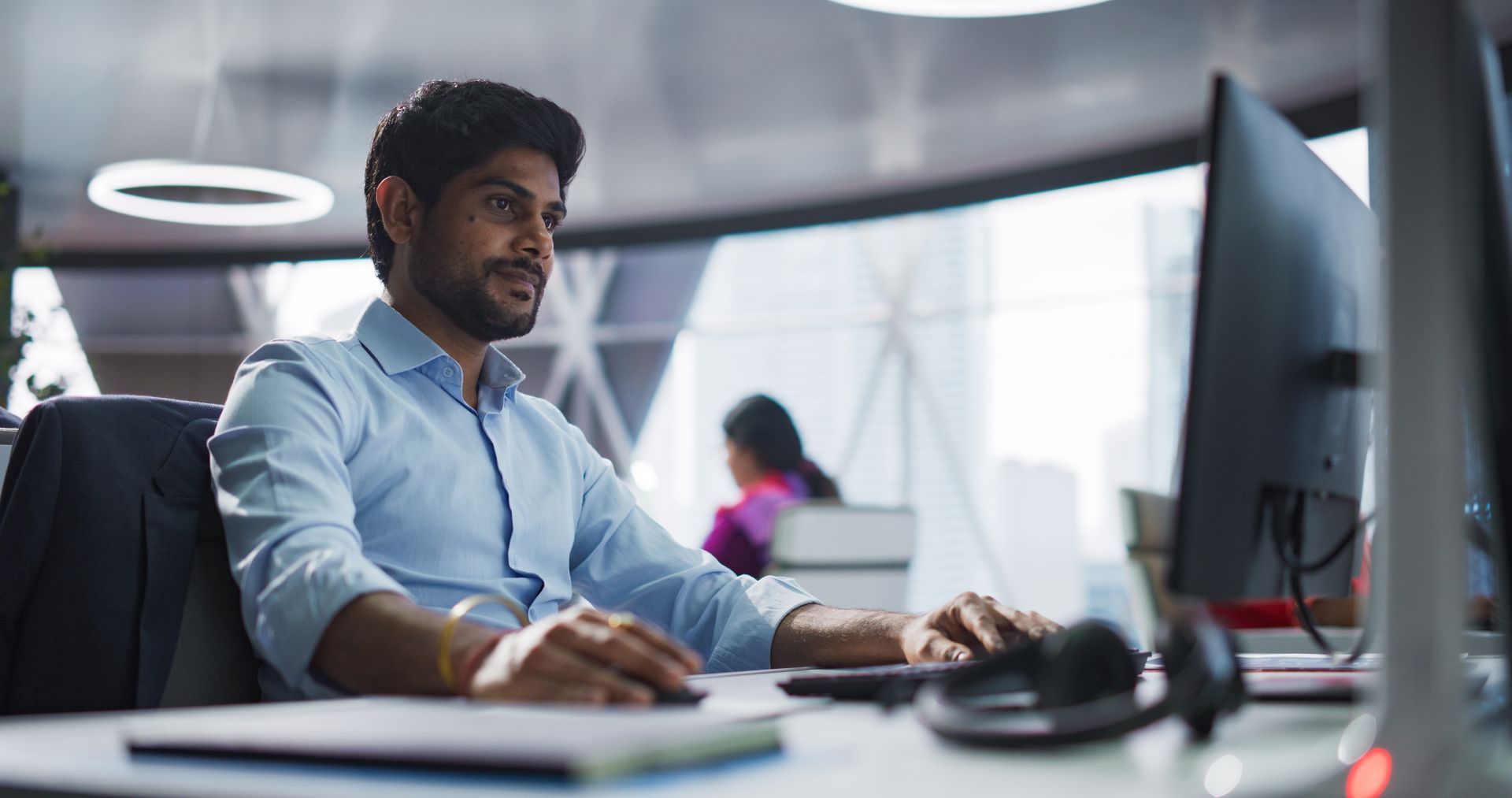 A man is sitting at a desk in front of a computer.