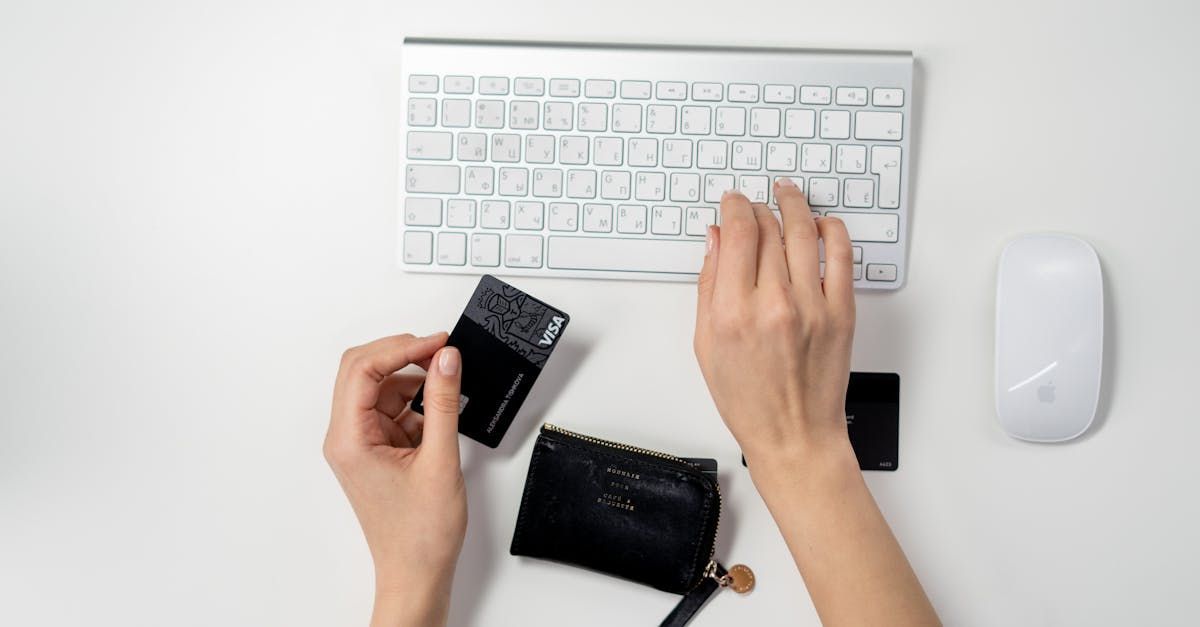 A person is typing on a keyboard while holding a credit card.