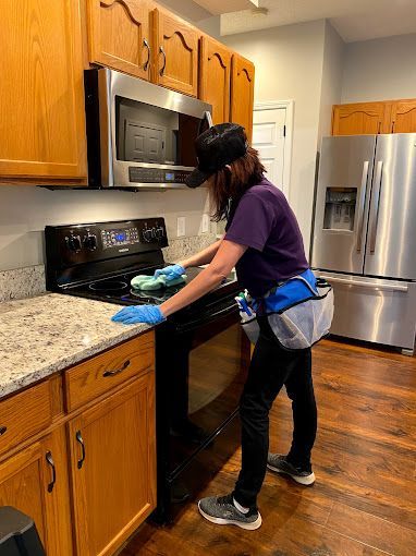 A woman is cleaning a stove in a kitchen.