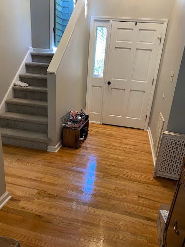 A hallway with hardwood floors , stairs and a door.