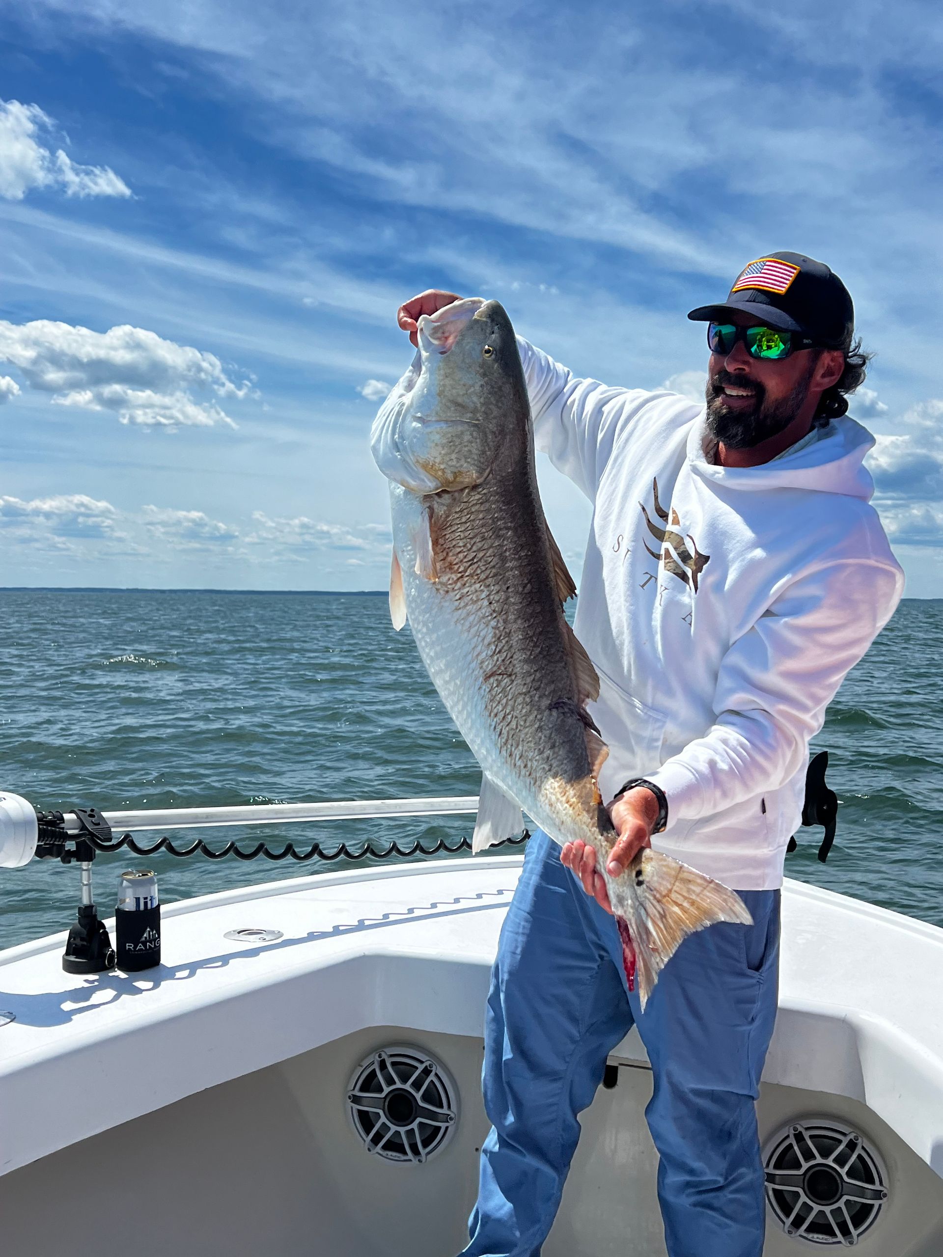 A man is holding a large fish on a boat.