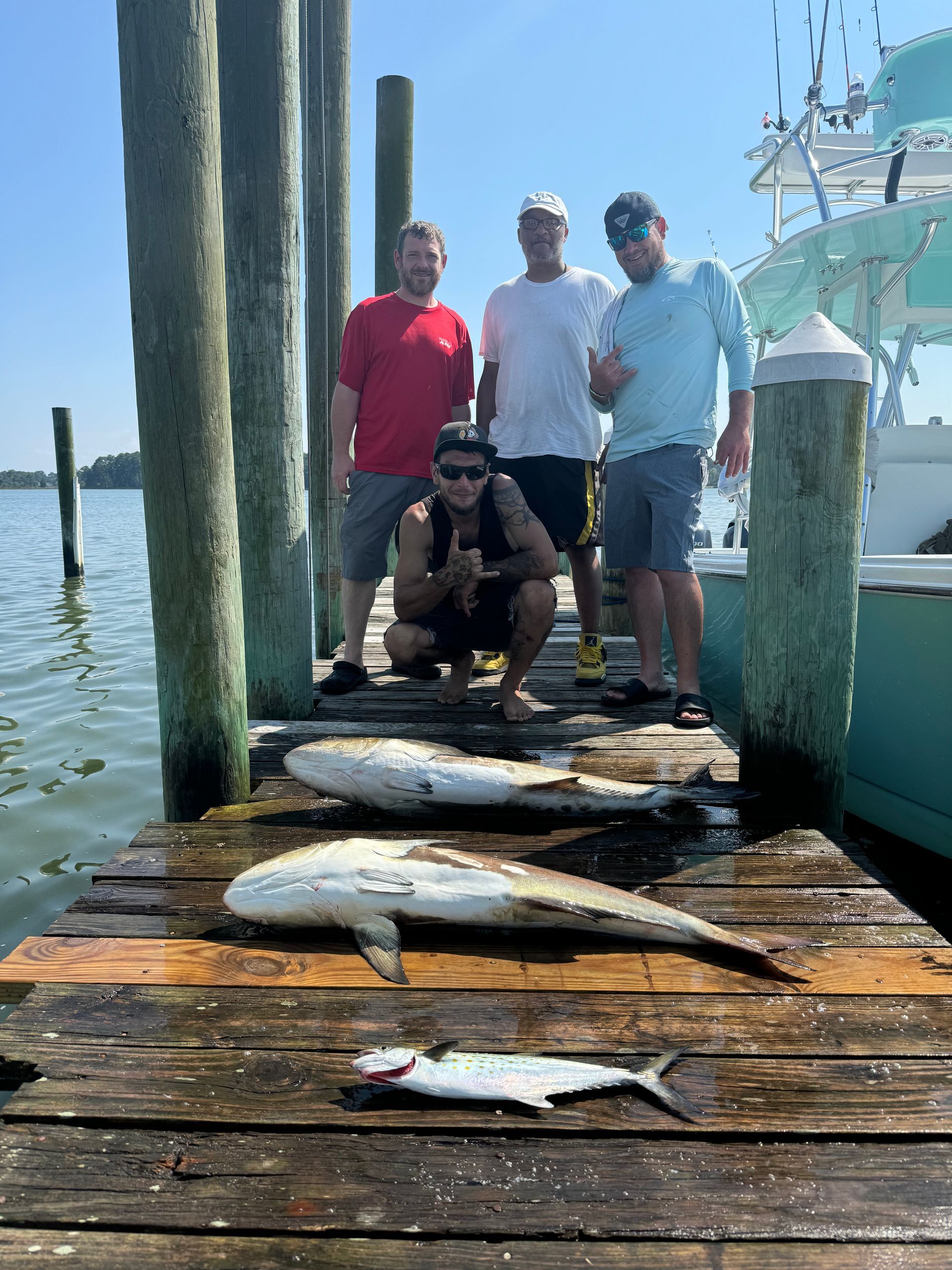 A group of men are posing for a picture on a dock with fish.