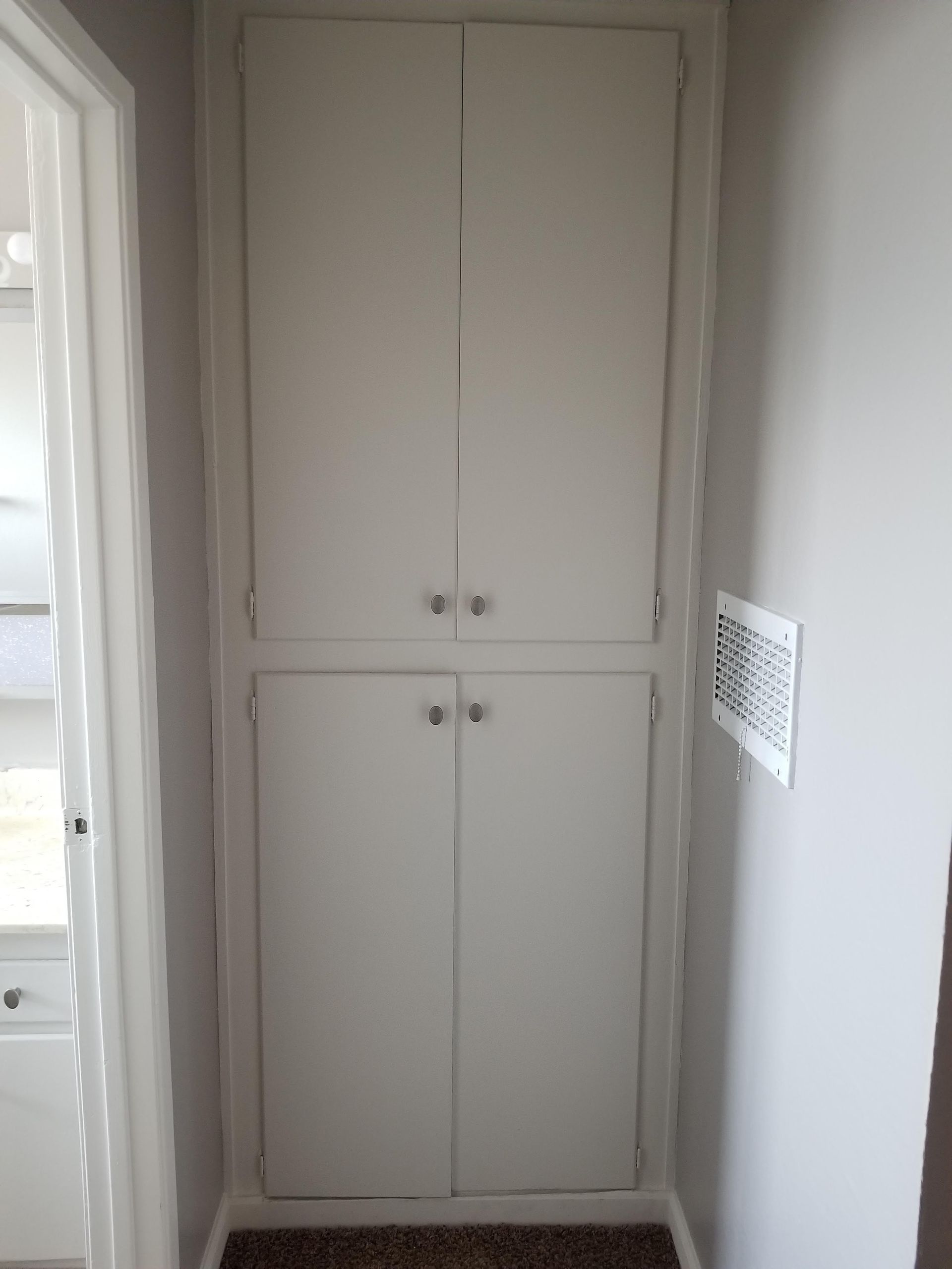 White built-in double closet doors in a narrow hallway.