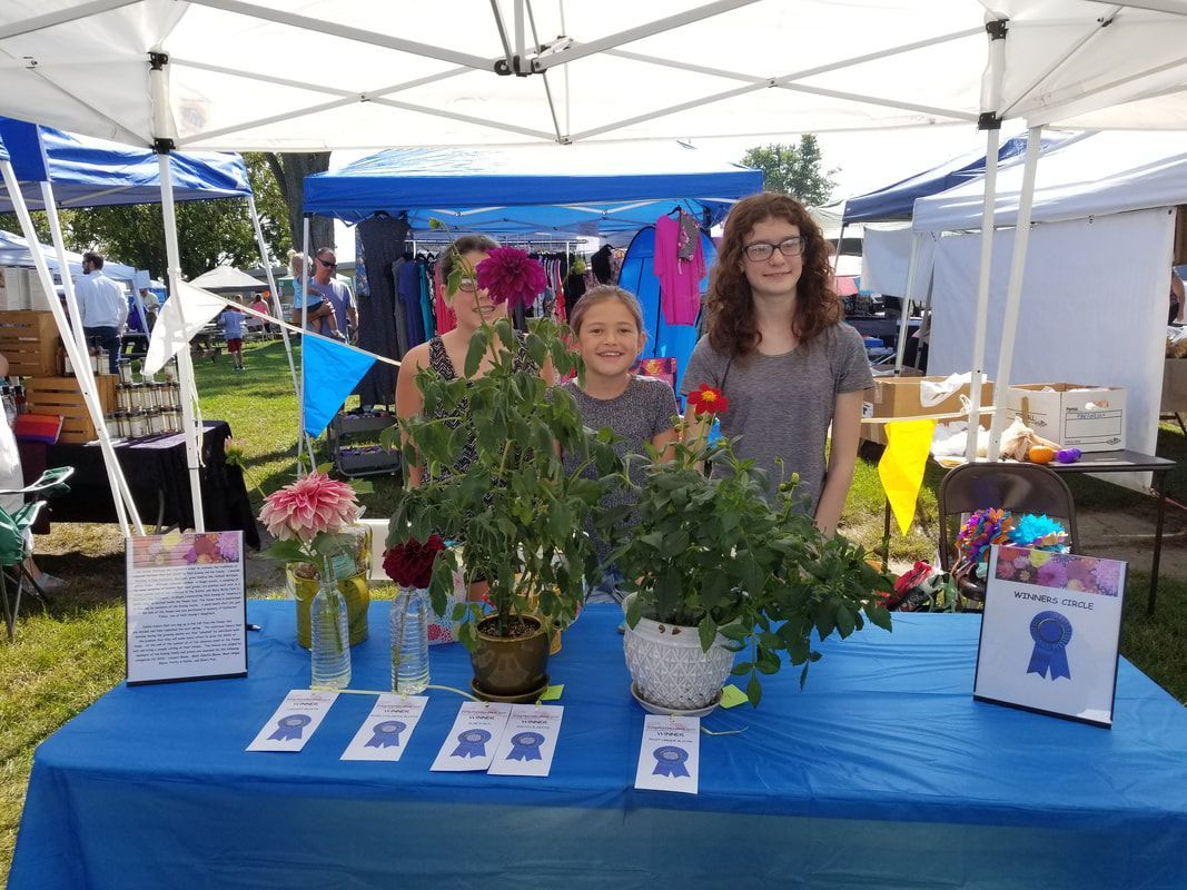 Two women and a child stand behind a table with flowers on it
