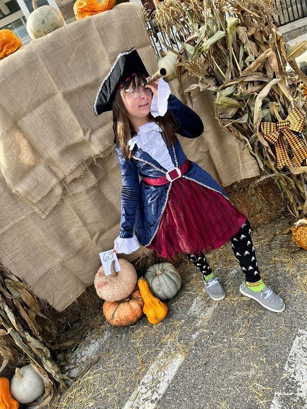 A girl wearing a pirate costume is looking through a spyglass