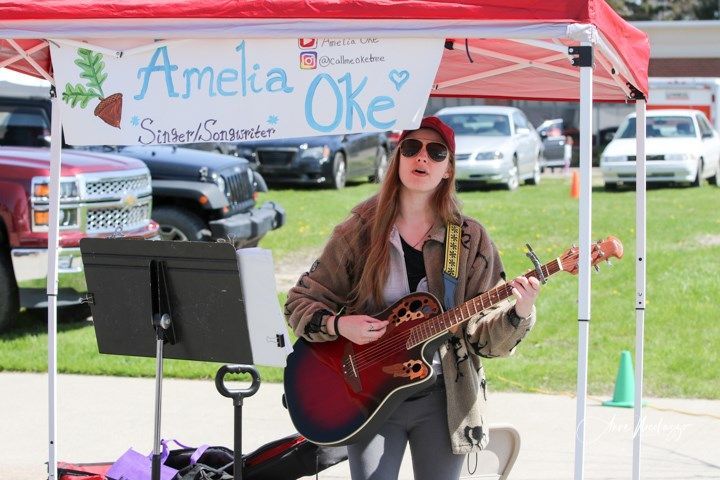 A woman playing a guitar under a sign that says amelia oke