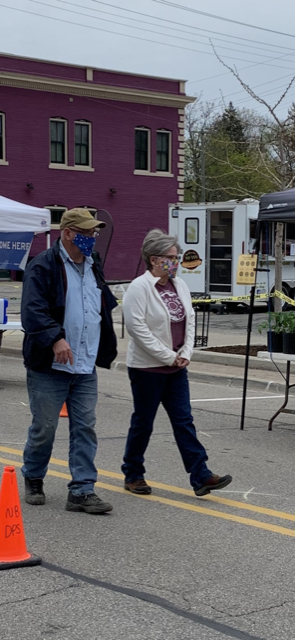 A man and a woman wearing face masks are walking down the street.