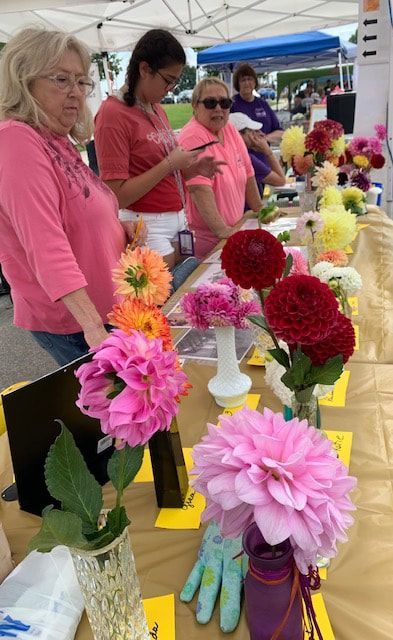 A group of women are sitting at a table with vases of flowers.