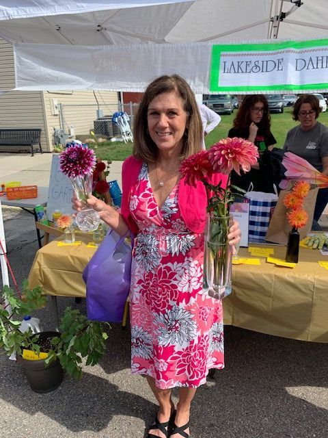 A woman in a pink dress is holding a vase of flowers.