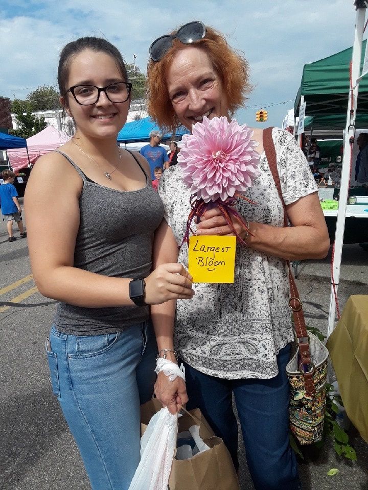 Two women standing next to each other holding flowers