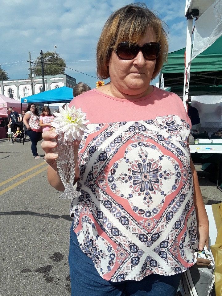 A woman wearing sunglasses is holding a flower in her hand