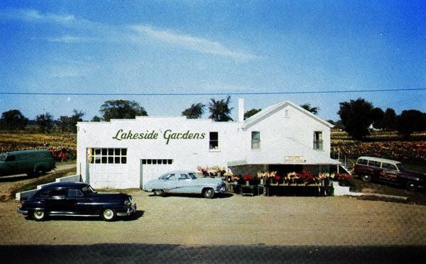 A black car is parked in front of a lakeside garage