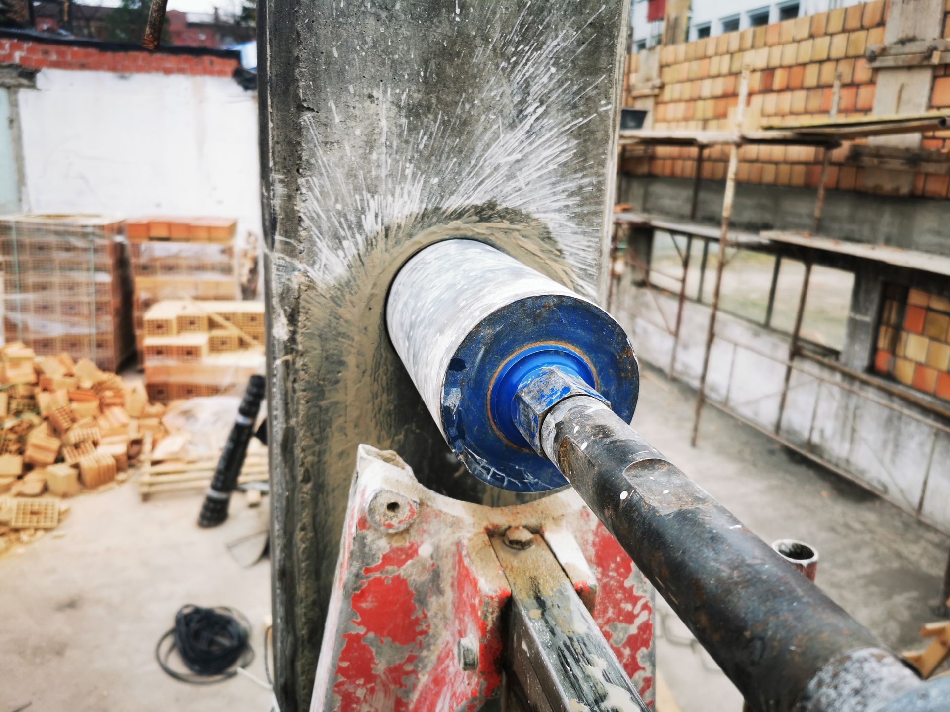 A hole cutting machine with an industrial diamond grain drilling a reinforced concrete column.