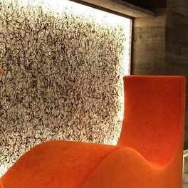 Une chaise orange est assise devant un mur avec une peinture dessus.