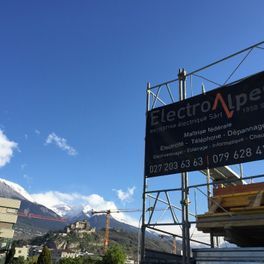 Un panneau sur un échafaudage avec des montagnes en arrière-plan.
