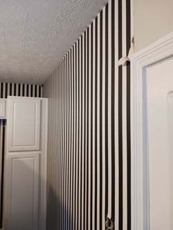 Black-and-white striped wallpaper in a hallway corner beside white doors and a ceiling line
