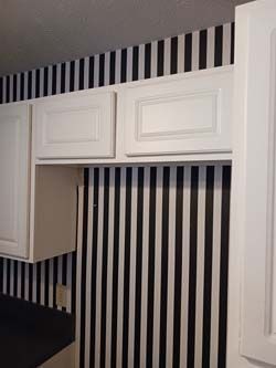 White kitchen cabinets above a black-and-white striped wall and backsplash area