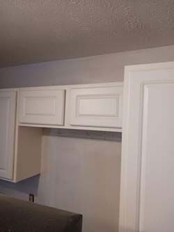 White kitchen cabinets above an empty counter or appliance space with a ceiling light visible