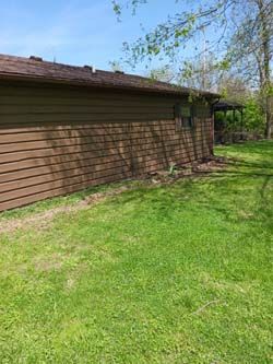 Brown house exterior with green lawn and trees along the side yard