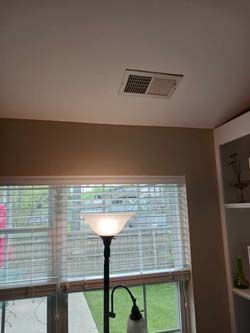Living room with windows, a floor lamp, and ceiling vent beneath a slanted ceiling