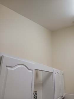 White cabinets beneath a beige wall and ceiling in a room corner