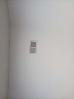 White wall with a small rectangular vent near the upper center.