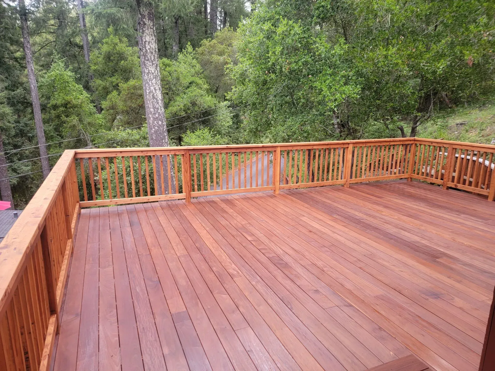 Wooden deck with railings overlooking a wooded backyard and trees