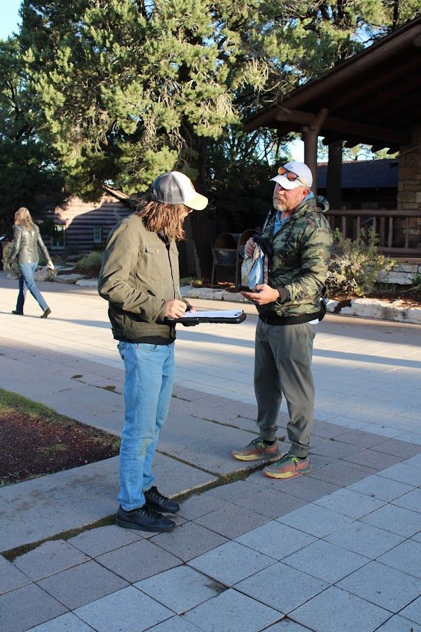 Two men are standing on a sidewalk talking to each other.