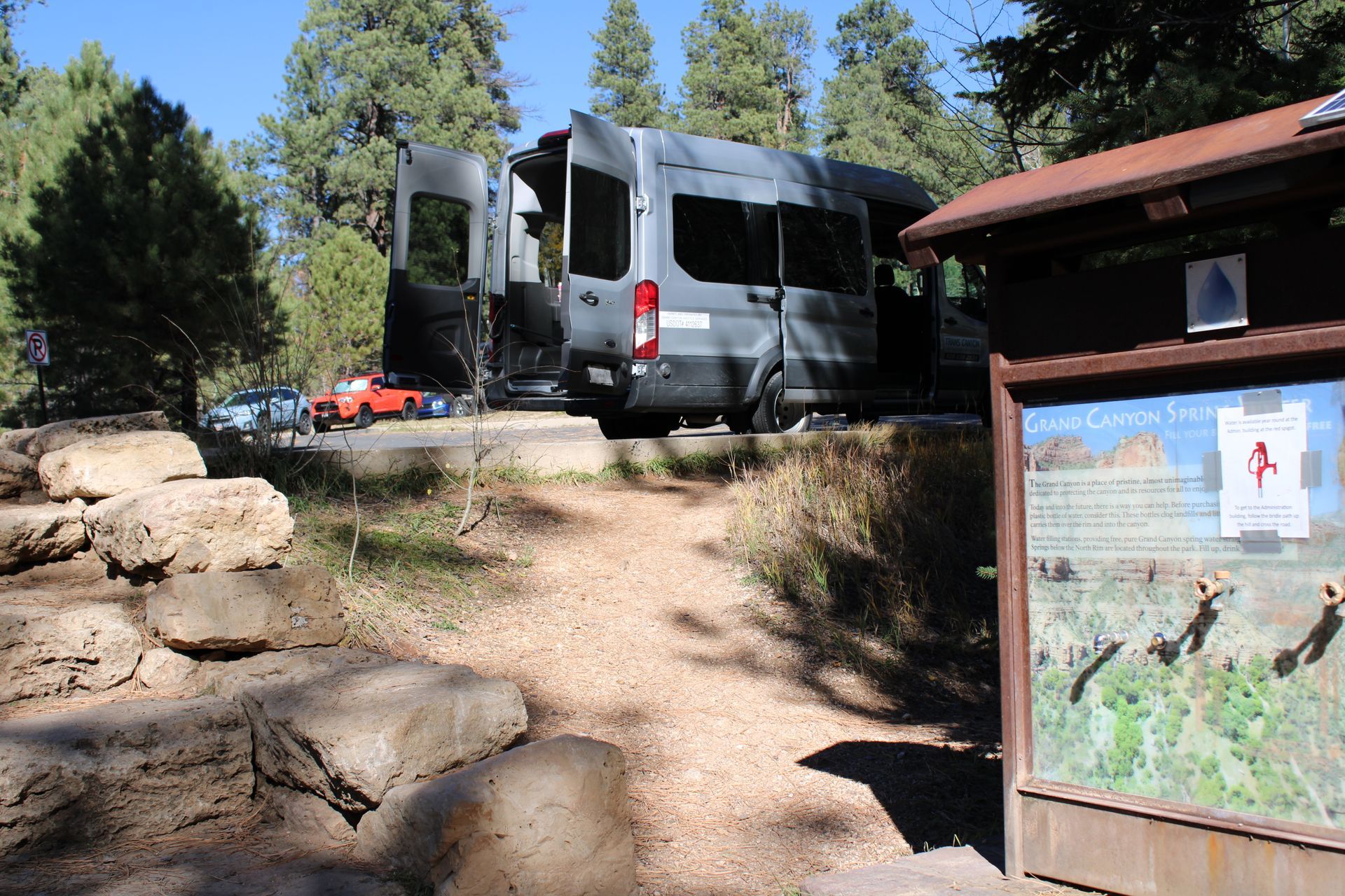 A van is parked on a dirt road next to a map